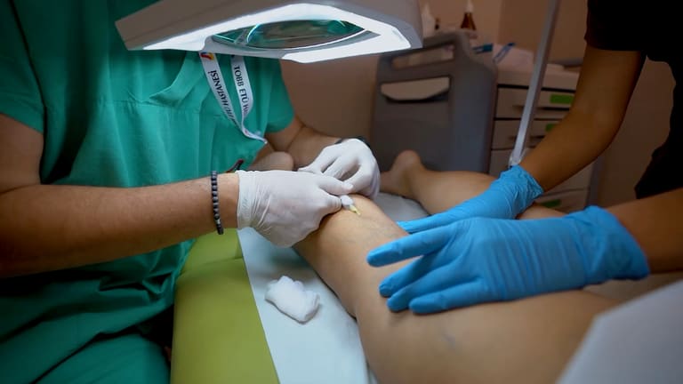 Klinikte bacakta, eldivenli ellerle uygulanan bir işlem